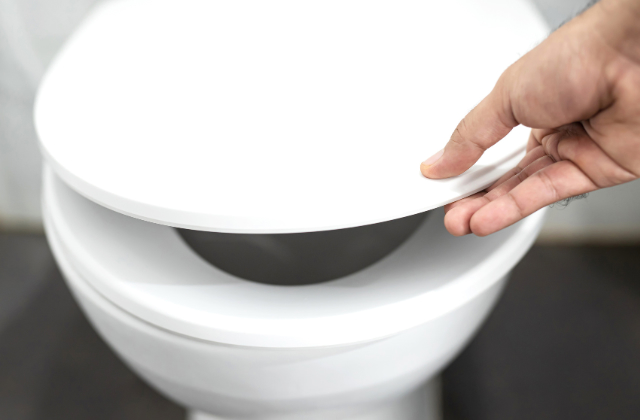トイレの蓋を開けようとしている手
