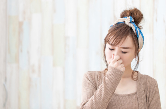 鼻をつまんでいる女性
