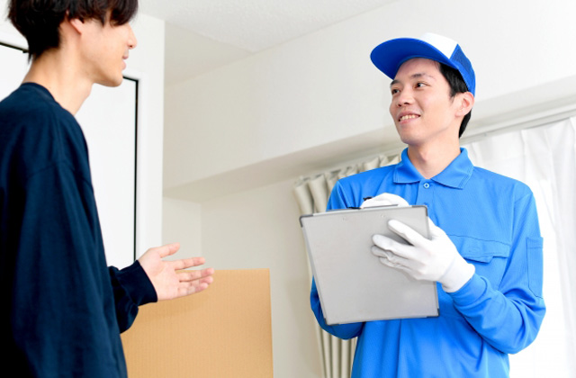 男性の客と話している青い服を着たリフォーム業者