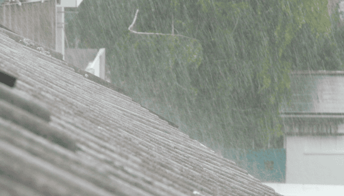 土砂降りの雨と古い一戸建ての屋根
