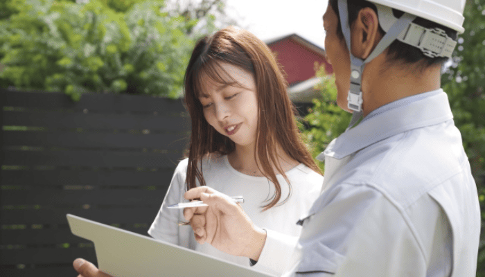 屋根の雨漏り修理について業者と相談する女性