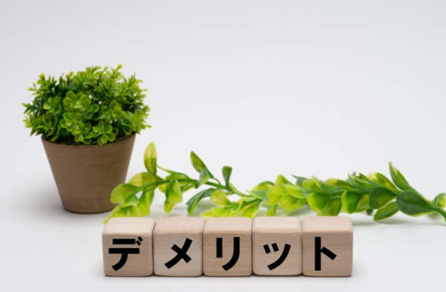 デメリットと書かれたブロックと植物