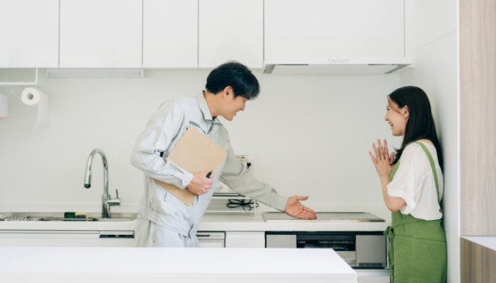 IHキッチンについてリフォームの提案をする業者と説明を受ける女性