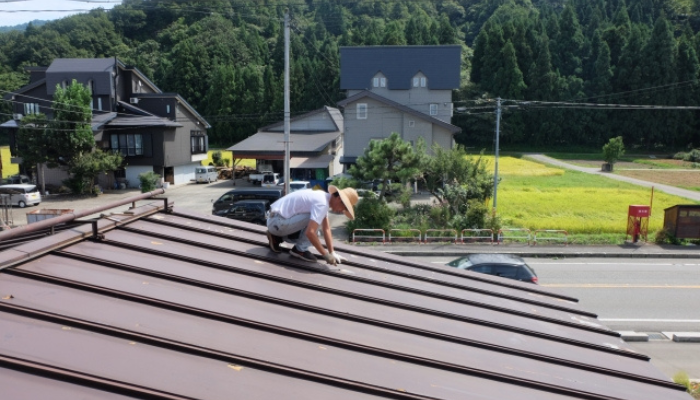 トタン屋根の修理をする男性