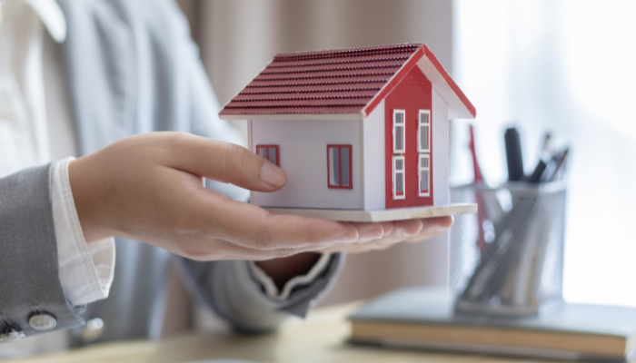 家の模型をもつ女性