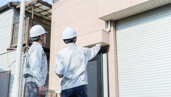 2人の工事員が壁を見ながら相談している様子